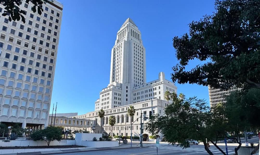 Low angle view of the iconic white Los Angeles City Hall building against a blue sky.